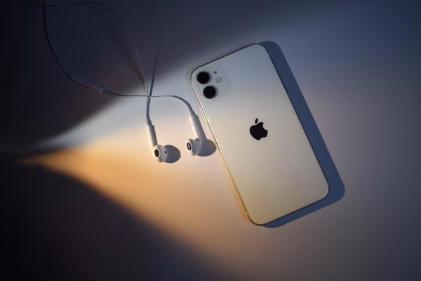 Photo of an iPhone and a pair of EarPods lying on a surface.